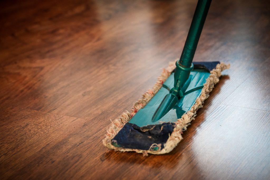 Mop with a worn cleaning pad resting on a polished wooden floor, illustrating home cleaning and maintenance.