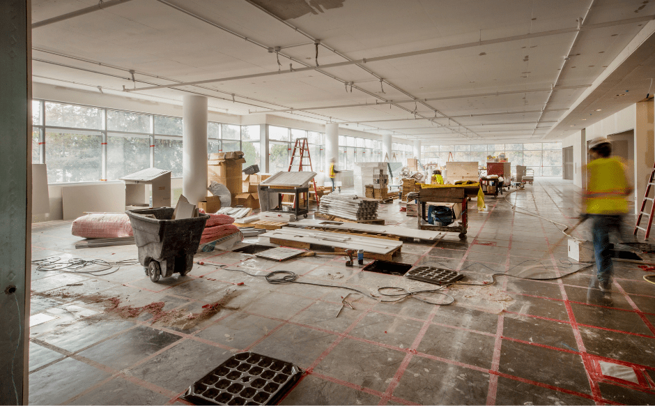 Construction site interior with tools, materials, and equipment scattered across the floor, showcasing an active renovation project.