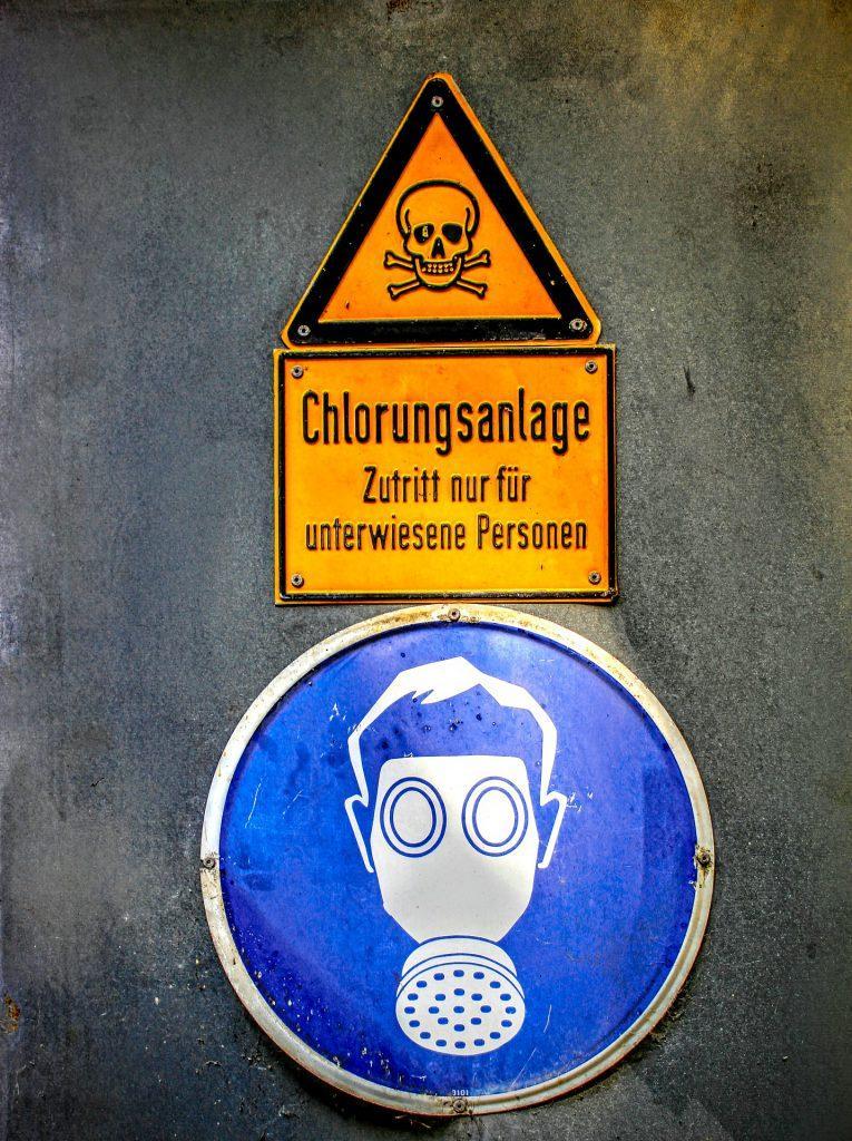 Warning signs indicating restricted access to a ventilation system, featuring a hazard symbol and an illustration of a person wearing protective goggles.