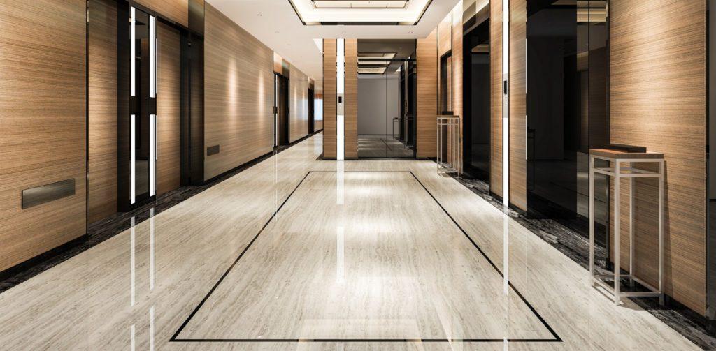 Modern hotel corridor featuring polished marble flooring, elegant lighting, and stylish wooden paneling, creating a sophisticated and inviting atmosphere.